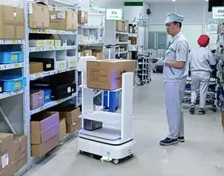 부품 선반 옆에서 작업자와 함께 있는 배송 로봇