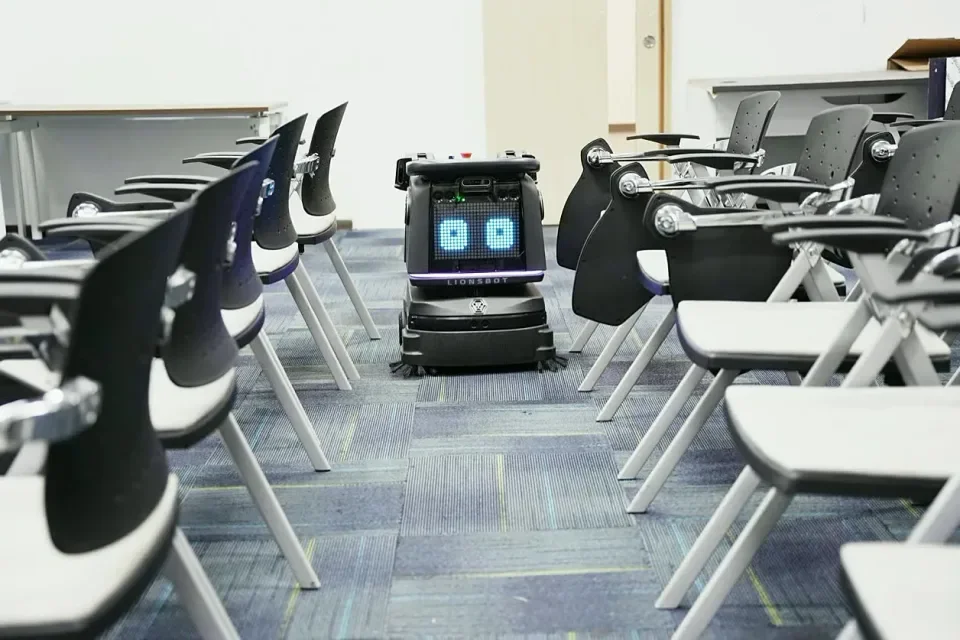 LionsBot R3 Vac가 강의실 좌석 사이 통로에 있는 모습
