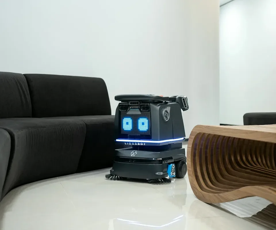 LionsBot R3 Vac가 라운지 소파 옆을 청소하는 모습
